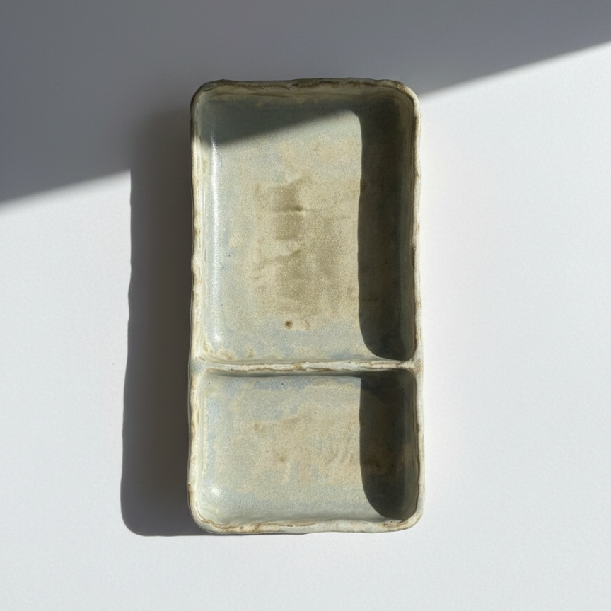Rectangular pottery object on a white surface with a gray background