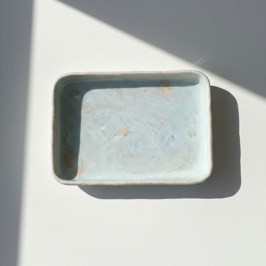 Small ceramic dish on a white surface with a gray background